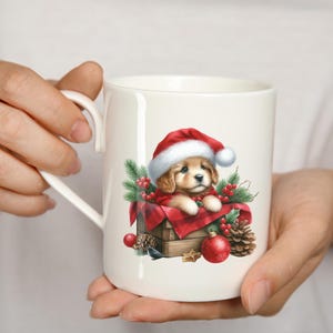 May include: White ceramic mug featuring a festive illustration of a puppy wearing a Santa hat, nestled in a wooden box with red plaid fabric. The design includes pine needles, red berries, and ornaments, perfect for the holiday season.