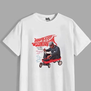 May include: A white short-sleeve t-shirt featuring a graphic of a person in a suit and hat sitting in a red wagon. The text reads "SOUPLESSE ET CONTRACTION" in red, along with "monk's music" and "thelonious monk septet" in smaller script.