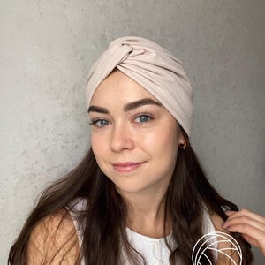 Pode incluir: Uma faixa de cabe&ccedil;a estilo turbante bege. O tecido &eacute; macio e franzido na parte superior, criando um design elegante e com n&oacute;s. Este acess&oacute;rio de cabe&ccedil;a &eacute; um acess&oacute;rio de moda para v&aacute;rias ocasi&otilde;es.
