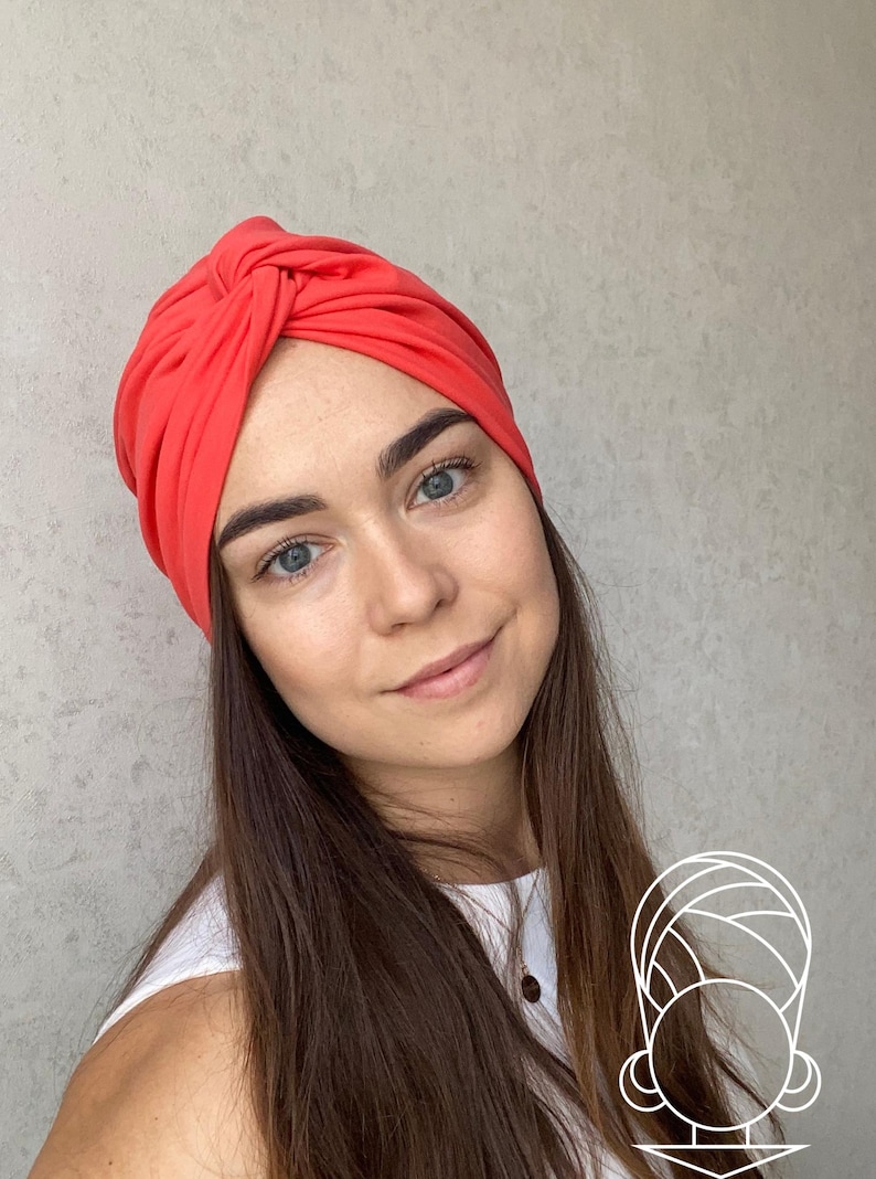 Pode incluir: Um turbante cor coral. O tecido &eacute; franzido e amarrado no topo, criando um acess&oacute;rio de cabe&ccedil;a elegante. Este acess&oacute;rio de cabe&ccedil;a &eacute; uma escolha elegante para v&aacute;rias ocasi&otilde;es.