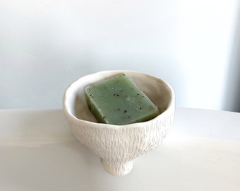 Ceramic soap dish with self-emptying, white soap dish with front outlet, functional and decorative at the same time. Round with slight relief.