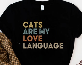 Peut inclure: T-shirt noir avec un graphisme de style vintage qui dit "Les chats sont ma langue d'amour".
