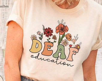 May include: A cream colored t-shirt with the words "DEAF education" in colorful letters with a floral design above the text.