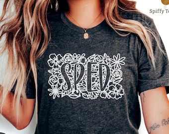 Könnte beinhalten: Dunkelgraues T-Shirt mit einem weißen Blumenmuster und dem Wort "SPED" in der Mitte.
