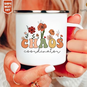 Może przedstawiać: Biały kubek emaliowany z kwiatowym wzorem i tekstem "CHAOS coordinator" w kolorowych retro literach.