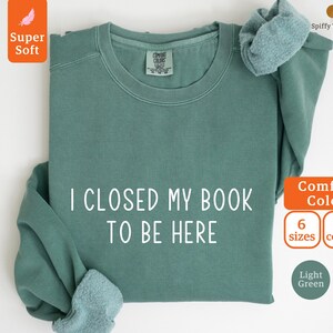May include: A light green sweatshirt with the text "I closed my book to be here" printed in white. The sweatshirt is available in 6 sizes and 8 colors.