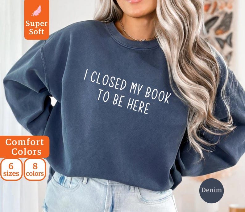 May include: A dark blue sweatshirt with the text "I closed my book to be here" in white. The sweatshirt is made of a soft, comfortable material.