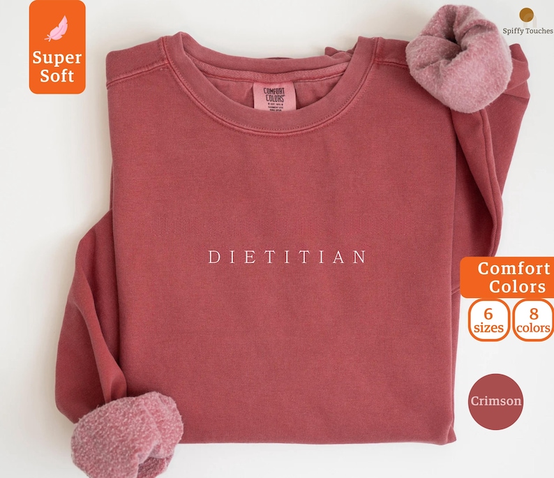May include: Crimson red sweatshirt with the word "DIETITIAN" printed in white on the front. The sweatshirt is made of a soft, comfortable fabric and is available in sizes 6 and 8.