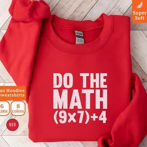 Puede incluir: Una sudadera roja Gildan con el texto blanco "DO THE MATH (9x7)+4". La sudadera también muestra "Gildan Hoodies & Sweatshirts", "6 tallas", "8 colores" y "ROJO". La esquina superior derecha tiene el texto "Super Soft".