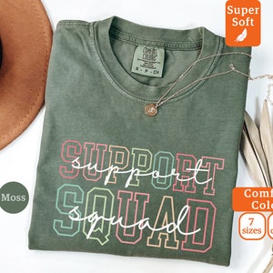 May include: A green t-shirt with the text "SUPPORT SQUAD" in rainbow colors. The shirt is made of a soft, comfortable fabric and is available in 7 sizes and 10 colors.