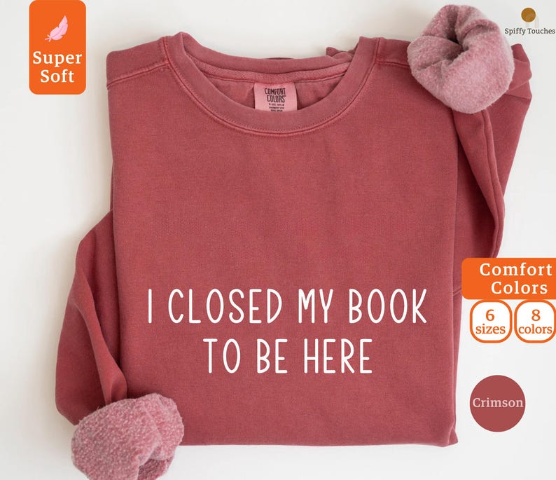 May include: Crimson red sweatshirt with the text "I CLOSED MY BOOK TO BE HERE" in white. The sweatshirt is available in 6 sizes and 8 colors.