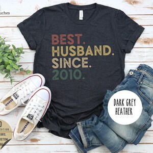 Puede incluir: Camiseta de color gris oscuro jaspeado con el texto "BEST. HUSBAND. SINCE. 2010." en una fuente de estilo vintage.