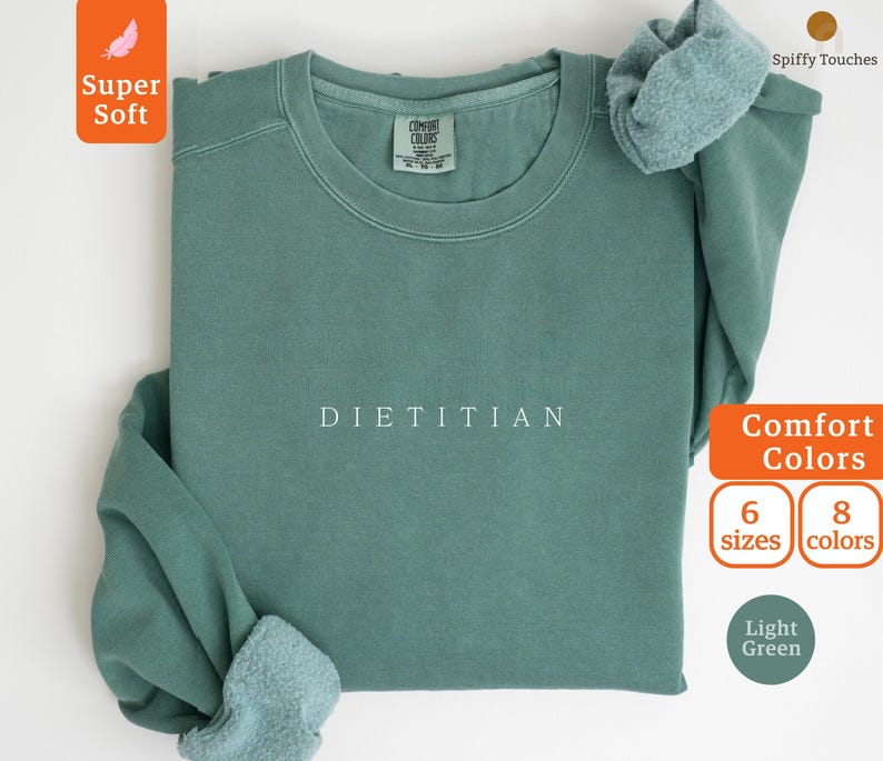 May include: A light green sweatshirt with the word "DIETITIAN" printed in white on the front. The sweatshirt is made of a soft, comfortable fabric and is available in 6 sizes and 8 colors.