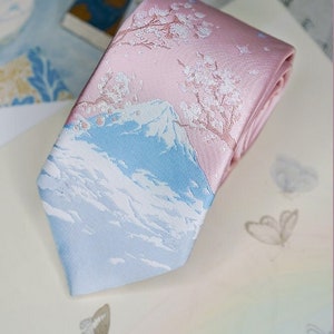 May include: A pink and blue silk tie with a white embroidered design of Mount Fuji and cherry blossoms.