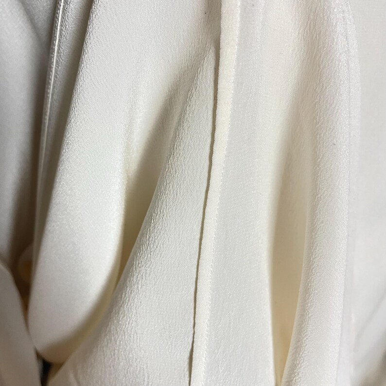 May include: Close-up of a white fabric with a seam down the center. The fabric is smooth and has a subtle texture.