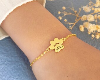 May include: A gold chain bracelet with a paw print charm engraved with the name "Milo".