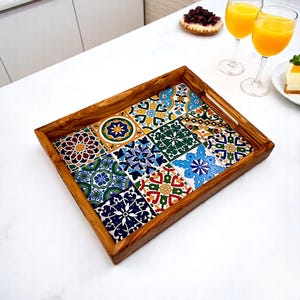 Puede incluir: Una bandeja rectangular de madera para servir con un diseño de azulejos decorativos. Los azulejos son coloridos y presentan patrones intrincados en tonos de azul, verde, amarillo, rojo y marrón. La bandeja tiene un acabado de madera natural y un asa en un lado.