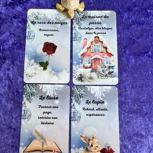May include: Four tarot cards with winter-themed illustrations and French text. The cards feature images of a rose, a house, a book, and a rabbit. A gold turtle figurine sits atop the cards on a purple velvet surface.