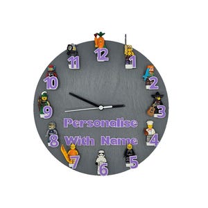 May include: Grey round clock with Lego minifigures representing each hour. The clock face has purple numbers and the text "Personalise With Name".
