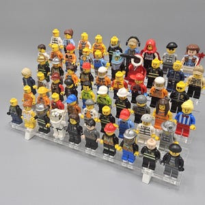 May include: A collection of over 50 colourful Lego minifigures displayed on a clear acrylic stand. The minifigures represent a variety of professions, including police officers, firefighters, construction workers, and more.