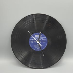 May include: A black vinyl record transformed into a clock. The clock face has a blue label with white text: "Good Music for Listening and Relaxation." The clock hands are white and black.