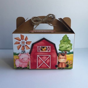 Può includere: Una scatola regalo in cartone marrone con manico. La scatola è decorata con un fienile rosso, un mulino a vento, un maiale, un cavallo e un pulcino giallo. La scatola ha uno sfondo bianco ed è perfetta per una festa a tema fattoria.