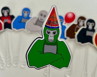 May include: A collection of colorful monkey-shaped cupcake toppers. The central topper features a green monkey wearing a party hat with the words "Happy Birthday." Other toppers include monkeys in various colors, with clear plastic sticks.