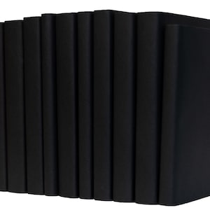 Peut inclure: Une pile de livres reli&eacute;s noirs, tous de la m&ecirc;me taille et forme, dispos&eacute;s en rang&eacute;e. Les livres sont tous ferm&eacute;s et ont une finition lisse et mate.