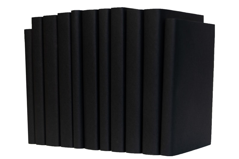 Peut inclure: Une pile de livres reli&eacute;s noirs, tous de la m&ecirc;me taille et forme, dispos&eacute;s en rang&eacute;e. Les livres sont tous ferm&eacute;s et ont une finition lisse et mate.