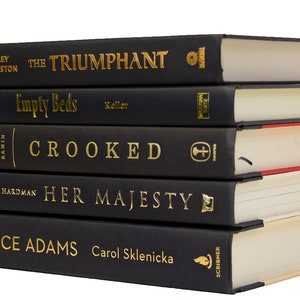 May include: A stack of five black hardcover books with gold lettering on the spines. The titles are "The Triumphant", "Empty Beds", "Crooked", "Her Majesty", and "Alice Adams".