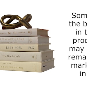 May include: A stack of five white books with gold lettering on the spines. The books are titled "Grace", "Listening is an Act of Love", "The Draw", "The One & Only", and "Juniper Tree Burning". A gold metal sculpture sits on top of the books. The text "Some of the books in this product may have remainder marks in ink." is visible to the right of the books.