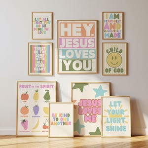 May include: A collection of nine framed wall art prints featuring pastel-colored typography and illustrations. The prints display religious phrases including Hey Jesus Loves You, Let All That You Do Be Done In Love, and Fruit Of The Spirit.