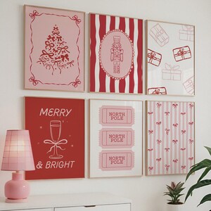May include: A collection of framed Christmas-themed art prints. The prints feature festive designs in red and pink, including a Christmas tree, nutcracker, gift boxes, and the words "Merry & Bright" and "North Pole".