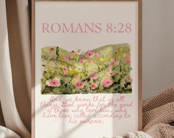 May include: A framed print with the text "ROMANS 8:28" in pink. Below the text is a watercolor painting of a field of pink and yellow flowers. The bottom of the print has a quote in pink script.