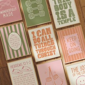May include: A collection of framed art prints with inspirational quotes and graphics. The prints feature various designs, including dumbbells, boxing gloves, and text such as "I Can Do All Things Through Christ" and "Keep On Going". The color palette includes pink, green, and white.