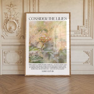 May include: Framed art print with the text "CONSIDER THE LILIES" at the top. The image features a floral design with a soft, textured background. Below the image is a quote from Luke 12:27-28.