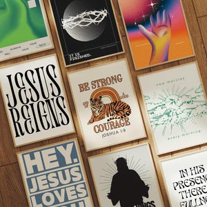 May include: A collection of eight inspirational wall art prints with Christian themes. The prints feature a variety of colors and designs, including a tiger, a crown of thorns, and a hand reaching up. The text on the prints includes phrases like "Jesus Reigns", "Be Strong", "New Mercies", and "In His Presence There Is Fullness".