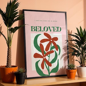 May include: A pink and green poster with a black frame. The poster features a stylized illustration of two red flowers with green leaves. The text on the poster reads "I am his and he is mine, BELOVED".