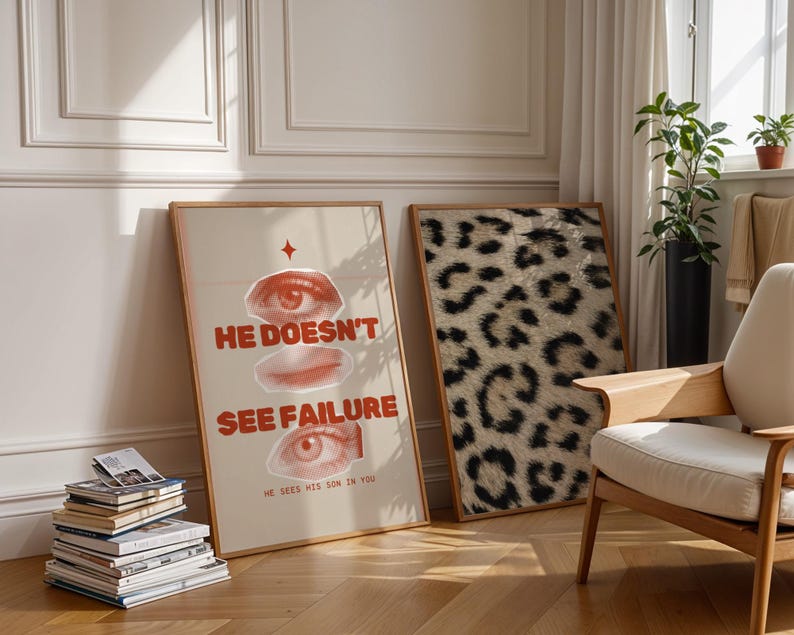 May include: Two framed posters on a white wall. The poster on the left features a red and white graphic with the text "He doesn't see failure. He sees his son in you." The poster on the right features a black and white animal print.