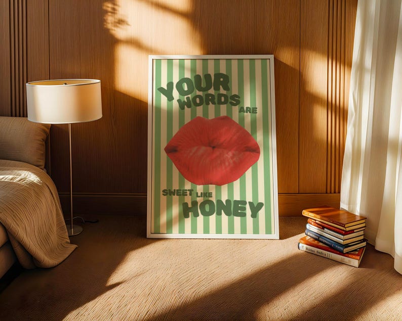 May include: A framed print with a green and white striped background. The print features a red lip with the text "Your words are sweet like honey".