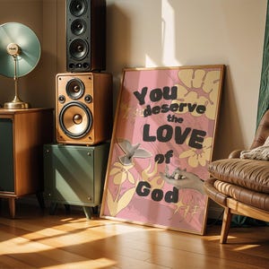 May include: Pink and yellow floral print poster with the text "You deserve the love of God" in black and white lettering.