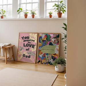 May include: Two framed prints on a wall. The print on the left is pink with the text "You deserve the LOVE of God". The print on the right is a collage of colorful paper scraps.
