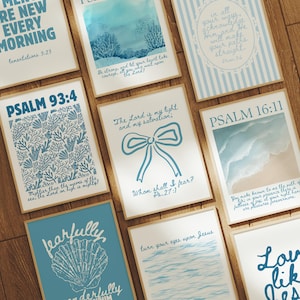 May include: A selection of framed art prints with uplifting quotes and Bible verses in blue and white. The prints showcase diverse designs, such as floral patterns, ocean scenes, and text. The frames have a natural wood finish.