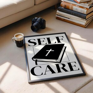 May include: Black and white print with the text "SELF CARE" in bold letters. A black book with a cross on the cover is in the centre of the print.