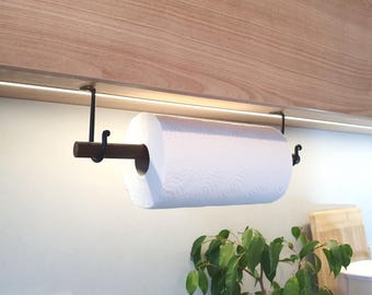 Peut inclure: Un porte-essuie-tout en métal noir avec une cheville en bois, monté sous une armoire en bois. Un rouleau d'essuie-tout blanc est maintenu en place. Le support est conçu pour être monté sous une armoire ou une étagère.