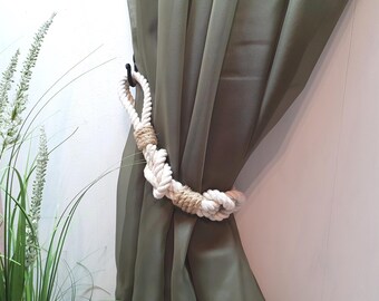May include: A white rope curtain tieback with a brown rope accent, holding back a green curtain.