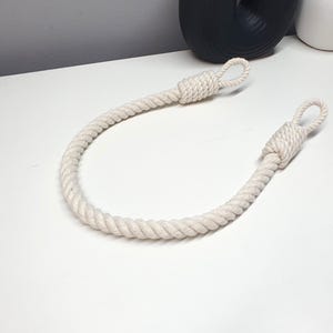 May include: A white cotton rope curtain tieback with two loops at each end.