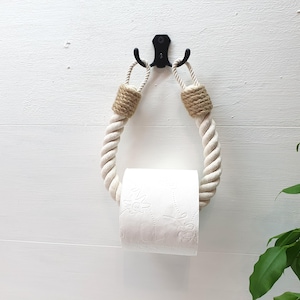 May include: A white rope toilet paper holder with a natural jute rope detail. The holder is mounted on a white wall.