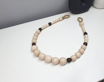 May include: A decorative wooden bead garland with natural wood beads and dark brown accent beads. The garland has loops at each end made of natural twine. This home decor item is designed to be hung or draped.