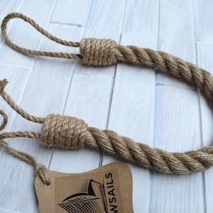 Pode incluir: Um amarrador de cortina de corda grossa e natural com duas al&ccedil;as em uma extremidade. A corda &eacute; feita de fibras naturais e tem um visual r&uacute;stico. A corda &eacute; amarrada em um n&oacute; na outra extremidade. A corda tem cerca de 76 cm de comprimento.